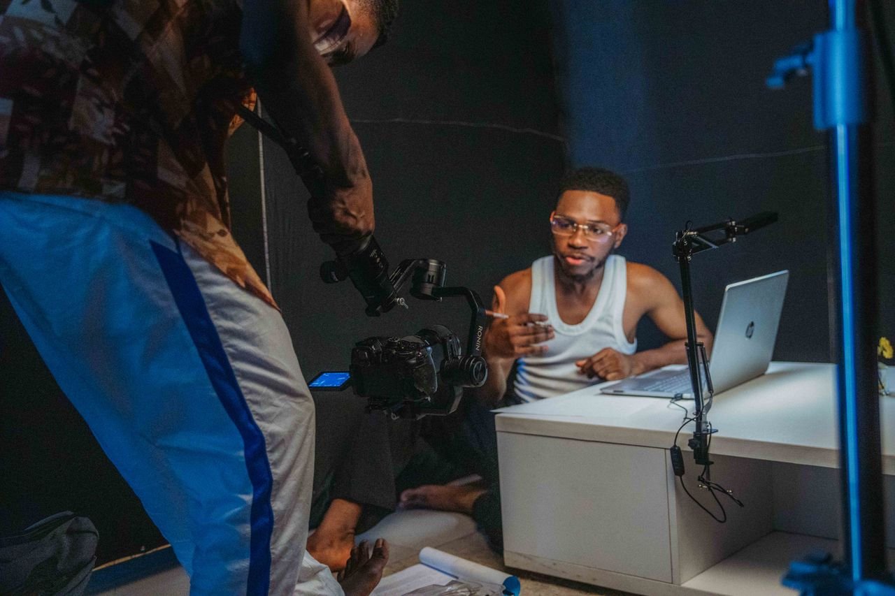 The Art of Drawing Readers In: Your attractive post title goes here Young black men filming a casual video with laptop and camera in a home studio setting.