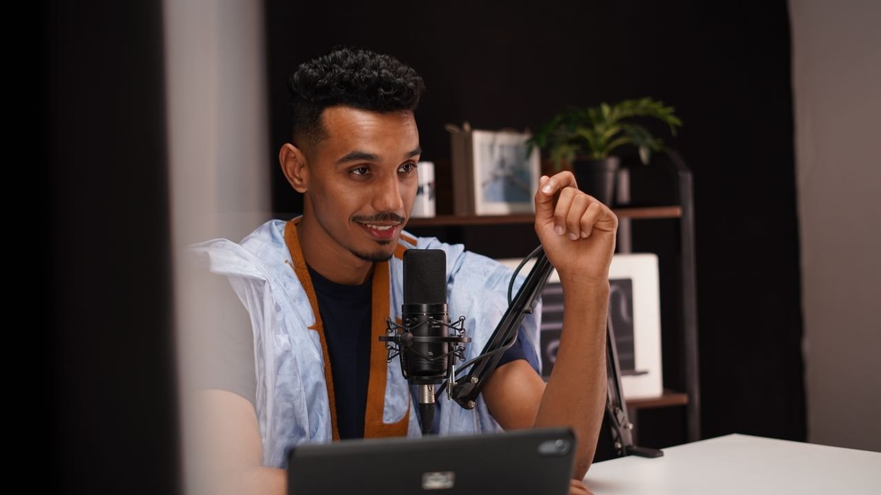 services-09 Confident young man speaking into a microphone during a podcast recording in a modern studio.