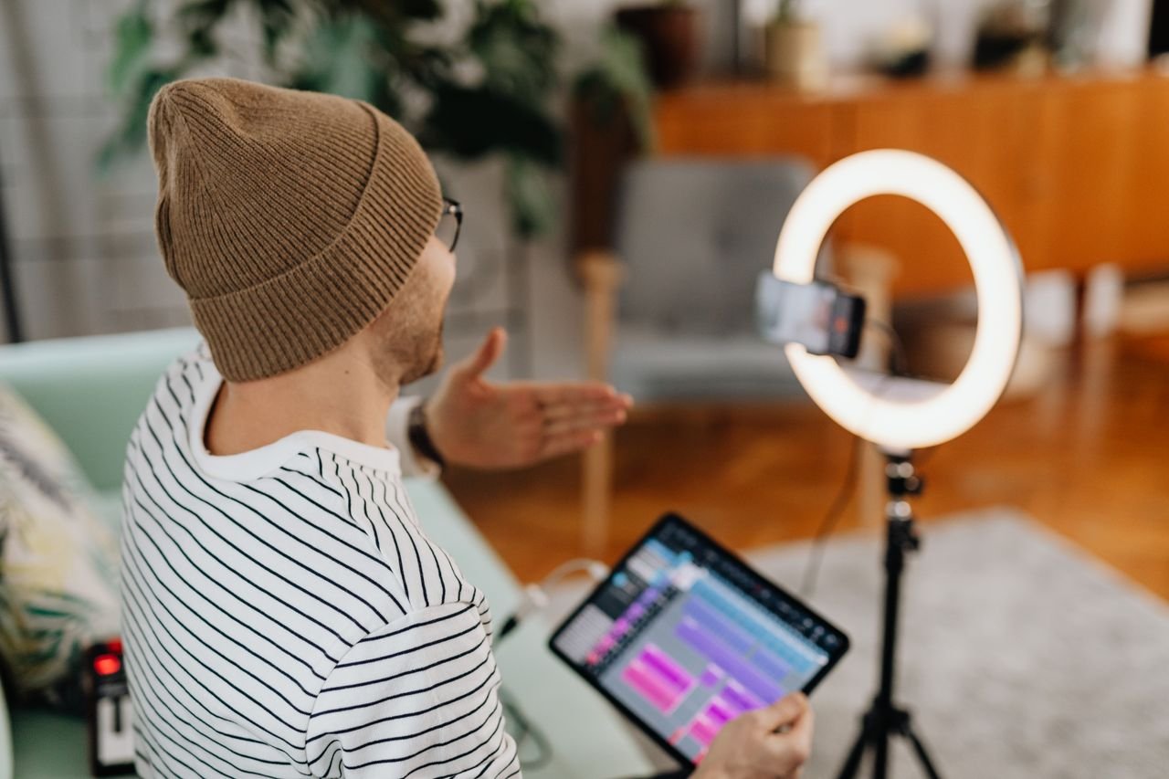 services-09 Adult male recording podcast using tablet and cellphone with ring light indoors